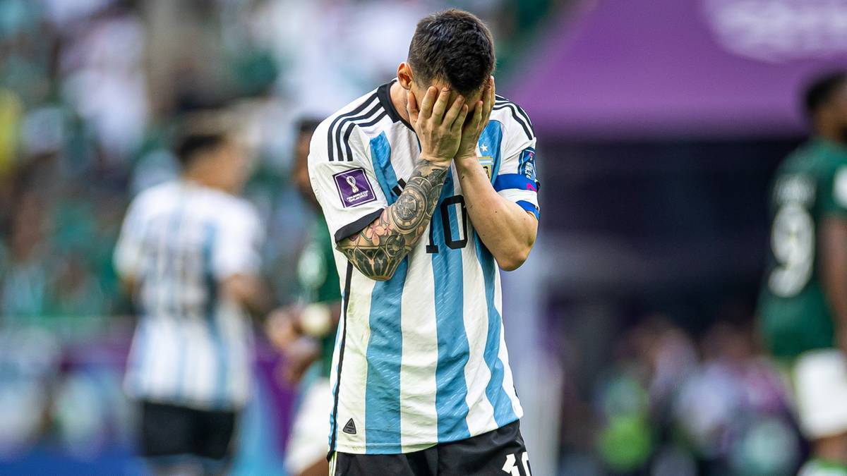 Lionel Messi w koszulce Argentyny trzyma się za twarz.