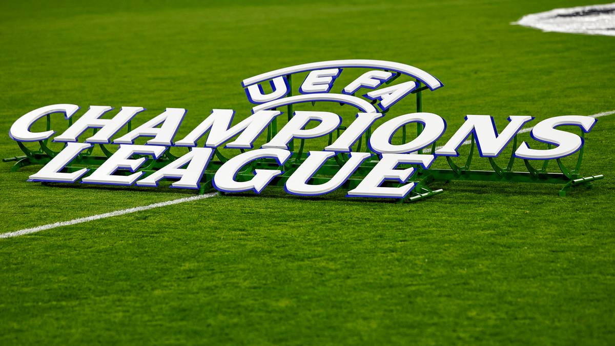 Napis "CHAMPIONS LEAGUE" na tle zielonej murawy stadionu piłkarskiego, z logiem UEFA w tle.
