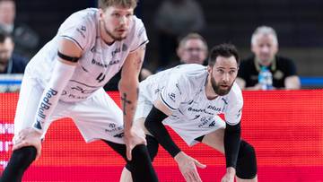 Dwóch siatkarzy PGE Projekt Warszawa w pozycji obronnej na boisku, przygotowujących się do akcji.