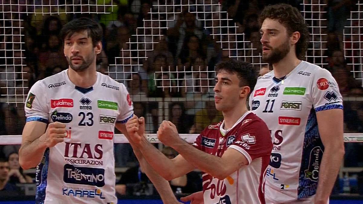 Trzech siatkarzy w strojach sportowych patrzy przed siebie. Dwóch z nich ma na koszulkach napisy "ITAS" i "FORST".