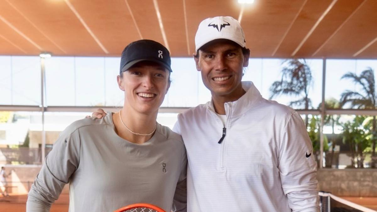 Iga Świątek i Rafael Nadal stoją razem na korcie tenisowym, oboje uśmiechnięci.