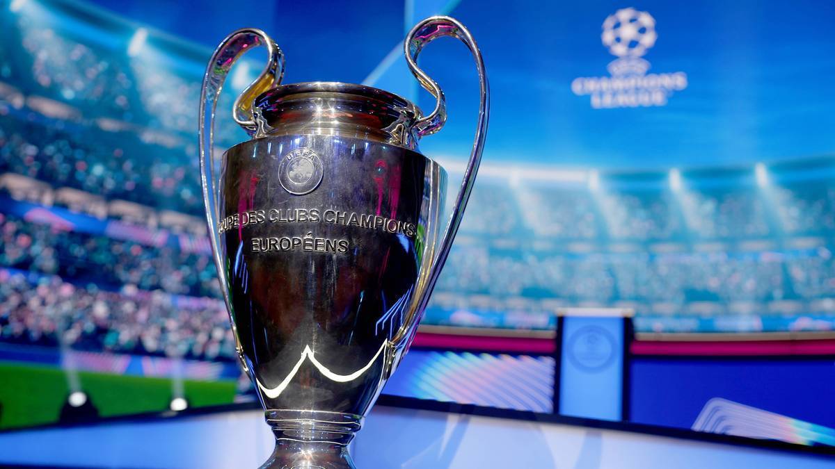 Trofeum Ligi Mistrzów UEFA na tle stadionu i logo rozgrywek.
