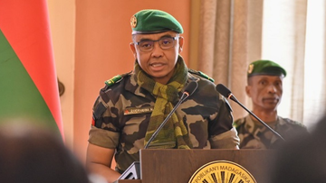 Przyw&oacute;dca wojskowy Madagaskaru, Michael Randrianirina, w mundurze i szaliku, przemawia za m&oacute;wnicą.