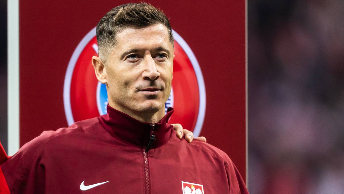 Robert Lewandowski w dresie reprezentacji Polski, z ręką na ramieniu innej osoby.