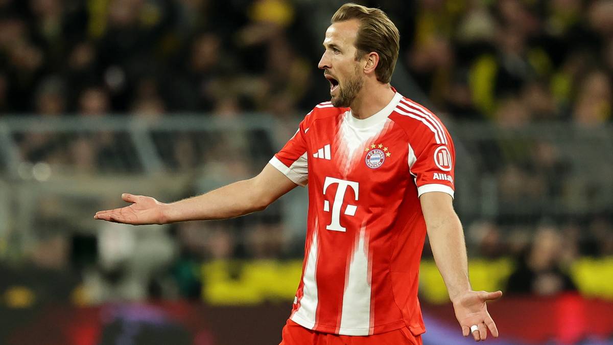 Harry Kane w czerwono-białej koszulce Bayernu Monachium, z otwartymi dłońmi, wyraża emocje podczas meczu.