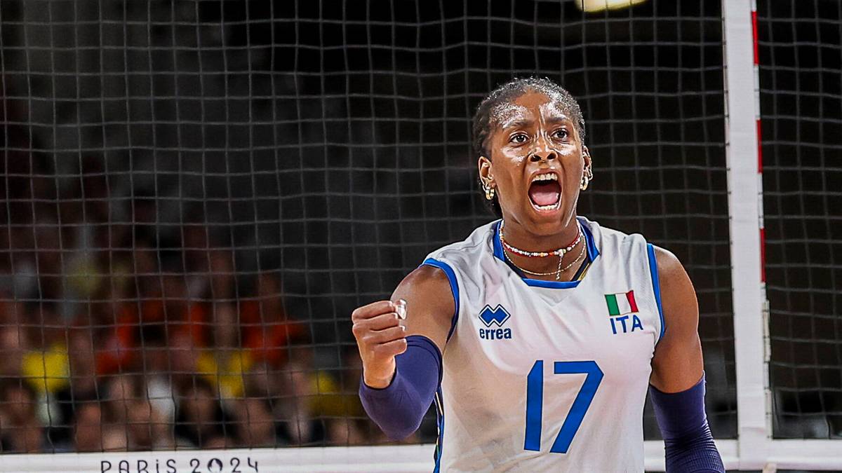 Siatkarka w białej koszulce z numerem 17 i napisem "ITA" na piersi, w geście radości i okrzyku, z mikrofonem w ręku.