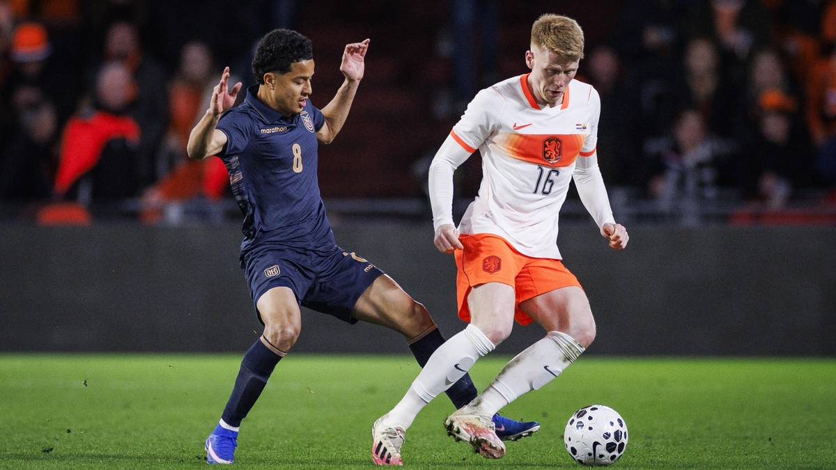 Dw&oacute;ch piłkarzy rywalizuje o piłkę nożną na boisku.