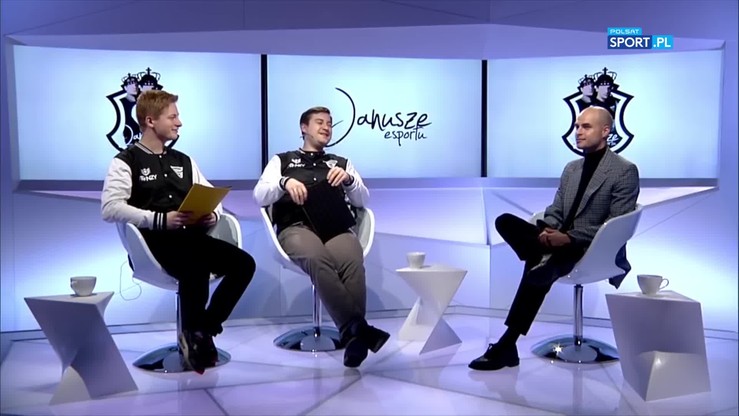 Trzech mężczyzn w studiu telewizyjnym, siedzących na krzesłach. Za nimi widoczne logo "Janusze esportu".