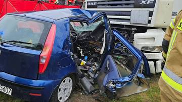 Rozbite niebieskie fiat punto uderzone w zaparkowanego białego tira.