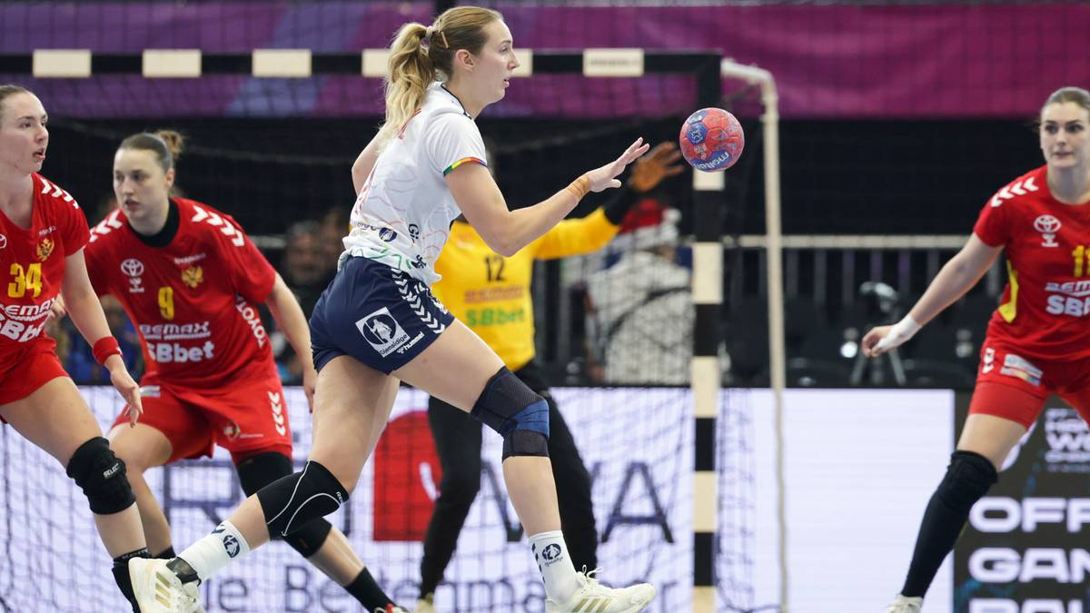 Piłkarka ręczna w białej koszulce i niebieskich spodenkach rzuca piłkę do bramki, po jej lewej stronie widać inne zawodniczki.