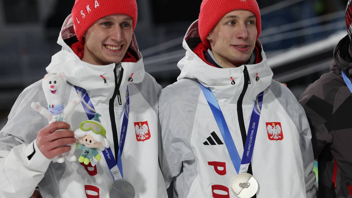 Dwóch polskich skoczków narciarskich w czapkach z napisem Polska i medalami na szyjach.