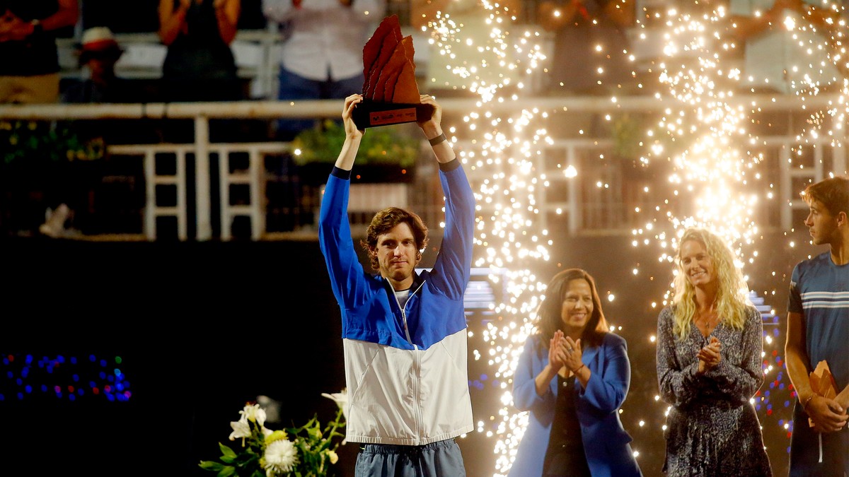 Nicolas Jarry podnosi trofeum w g&oacute;rę nad głową, otoczony sztucznymi ogniem i aplauzem publiczności.