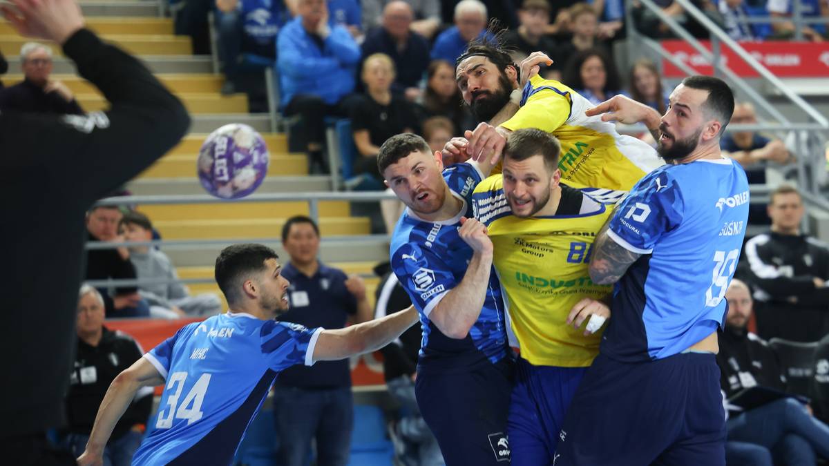 Zawodnicy piłki ręcznej w akcji walczą o piłkę na boisku.