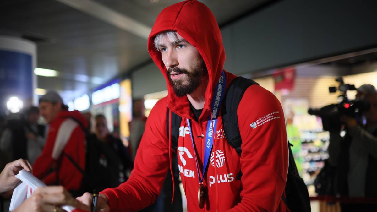 Mężczyzna w czerwonej bluzie z kapturem i plecakiem na ramieniu.