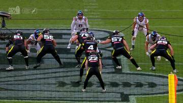 Drużyny zawodnik&oacute;w futbolu amerykańskiego ustawione na boisku, przygotowujące się do akcji.