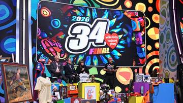 Scena z kolorowym tłem i napisem "2026 34 FINAL". Na pierwszym planie wystawione są r&oacute;żne przedmioty, w tym obrazy, ubrania, zabawki i pudełka.