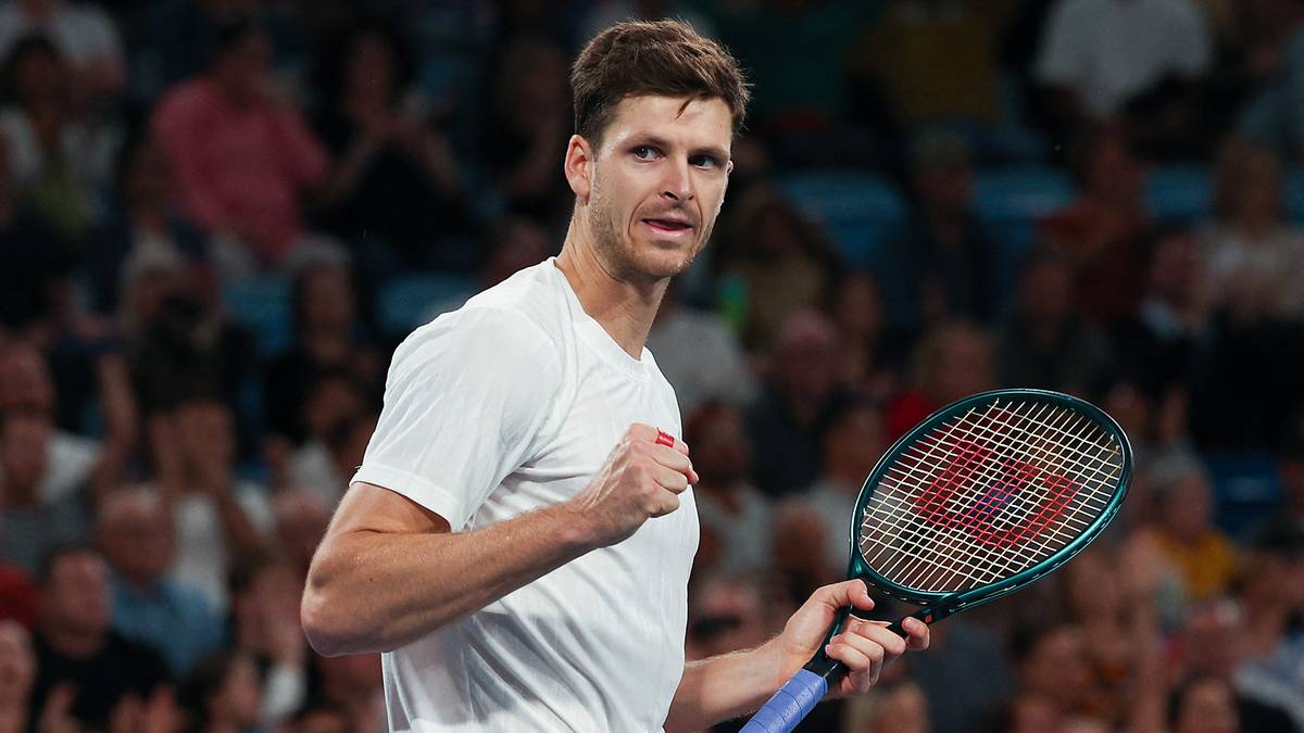 Hubert Hurkacz podczas meczu tenisowego, trzyma rakietę i uśmiecha się