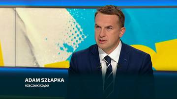 Portret mężczyzny ubranego w granatowy garnitur i krawat, siedzącego w studiu telewizyjnym.