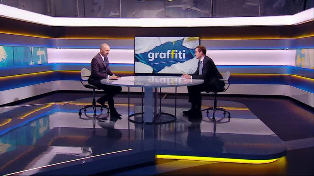 Dw&oacute;ch mężczyzn siedzi przy stole w studiu telewizyjnym "graffiti".