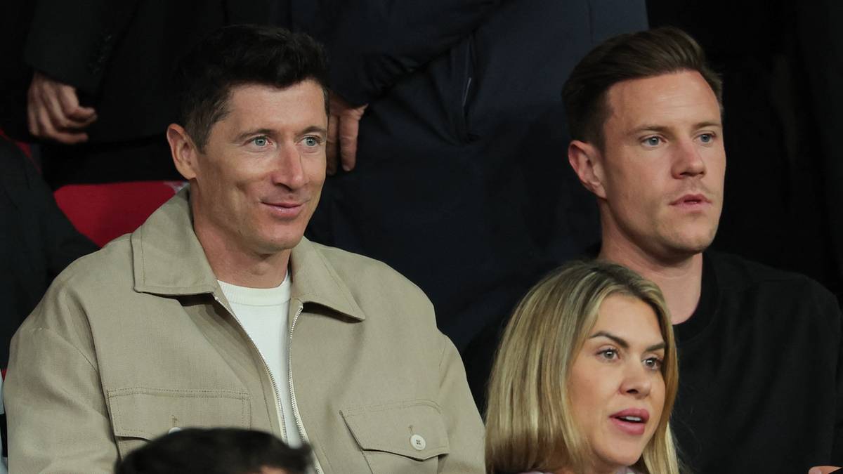 Trzech mężczyzn i kobieta siedzą na trybunach podczas meczu piłki nożnej.