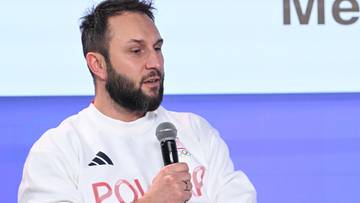 Mężczyzna w bluzie z napisem "POLSKA" m&oacute;wi do mikrofonu.