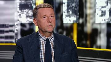 Marek Migalski w studiu telewizyjnym w granatowej marynarce i krawacie.