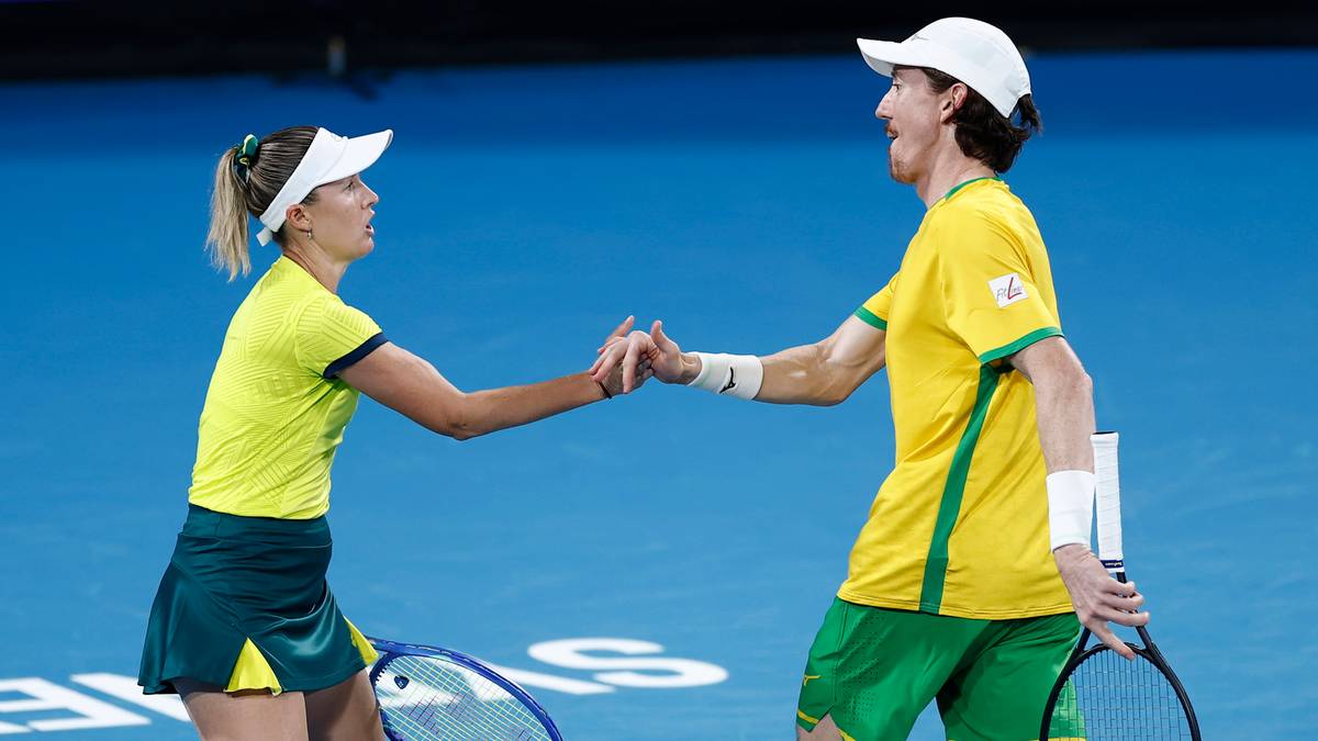 Dwaj tenisiści, kobieta i mężczyzna, w strojach sportowych w kolorach Australii, podają sobie ręce na korcie tenisowym po zakończonym meczu.