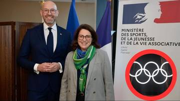 Mężczyzna i kobieta stoją przed flagami i logo.