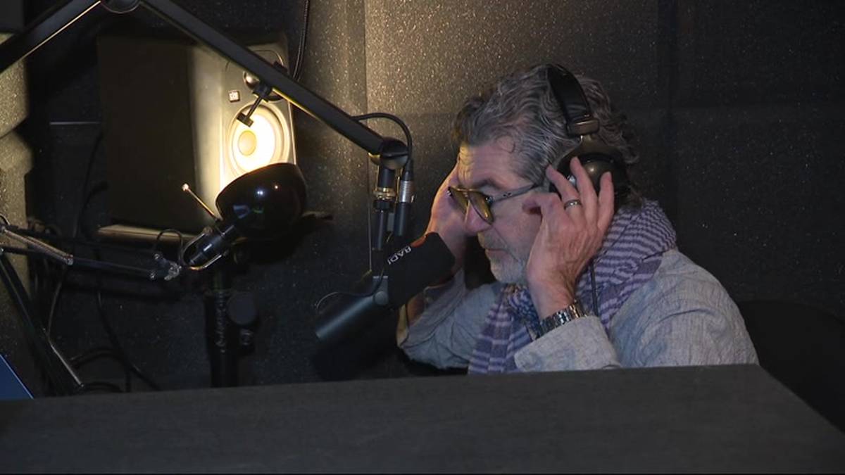 Starszy mężczyzna w studiu nagraniowym zakłada słuchawki.