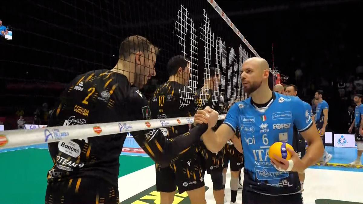 Dw&oacute;ch siatkarzy po meczu podaje sobie ręce po przeciwnych stronach siatki.