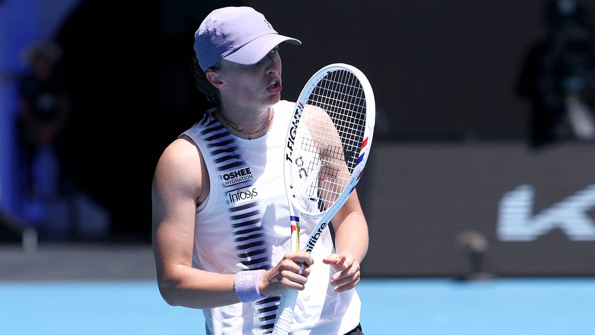 Iga Świątek podczas meczu tenisowego, trzyma rakietę i patrzy w bok.