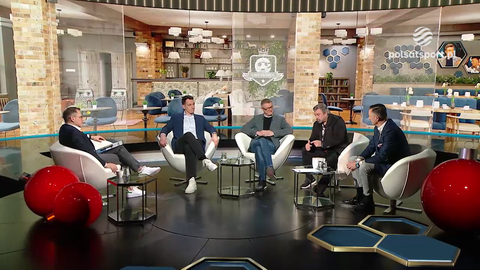 Czterech mężczyzn siedzi w fotelach podczas dyskusji w studiu telewizyjnym.