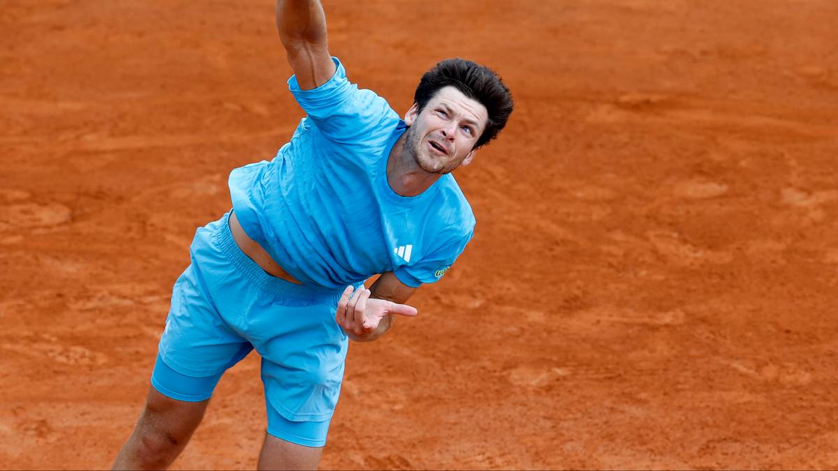 Tenisista Hubert Hurkacz wykonuje serwis na korcie ziemnym.