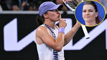 Iga Świątek w białej koszulce i fioletowej czapce z daszkiem, trzymająca rakietę tenisową i wykonująca gest ciszy.