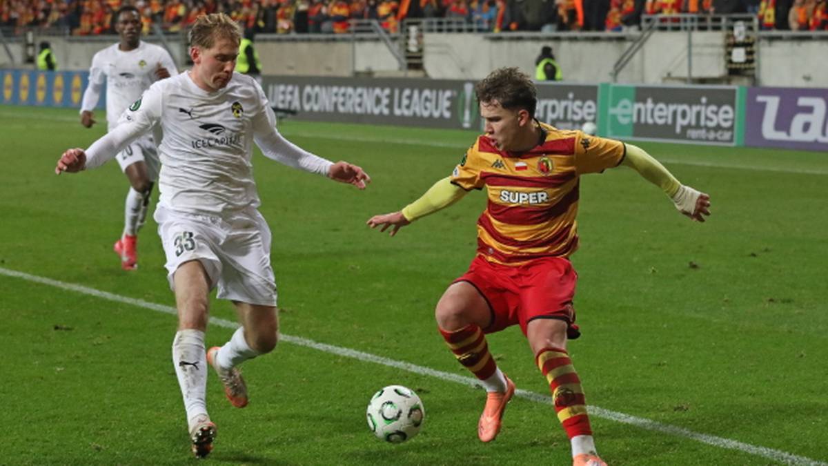 Dwóch młodych piłkarzy walczących o piłkę na boisku podczas meczu.