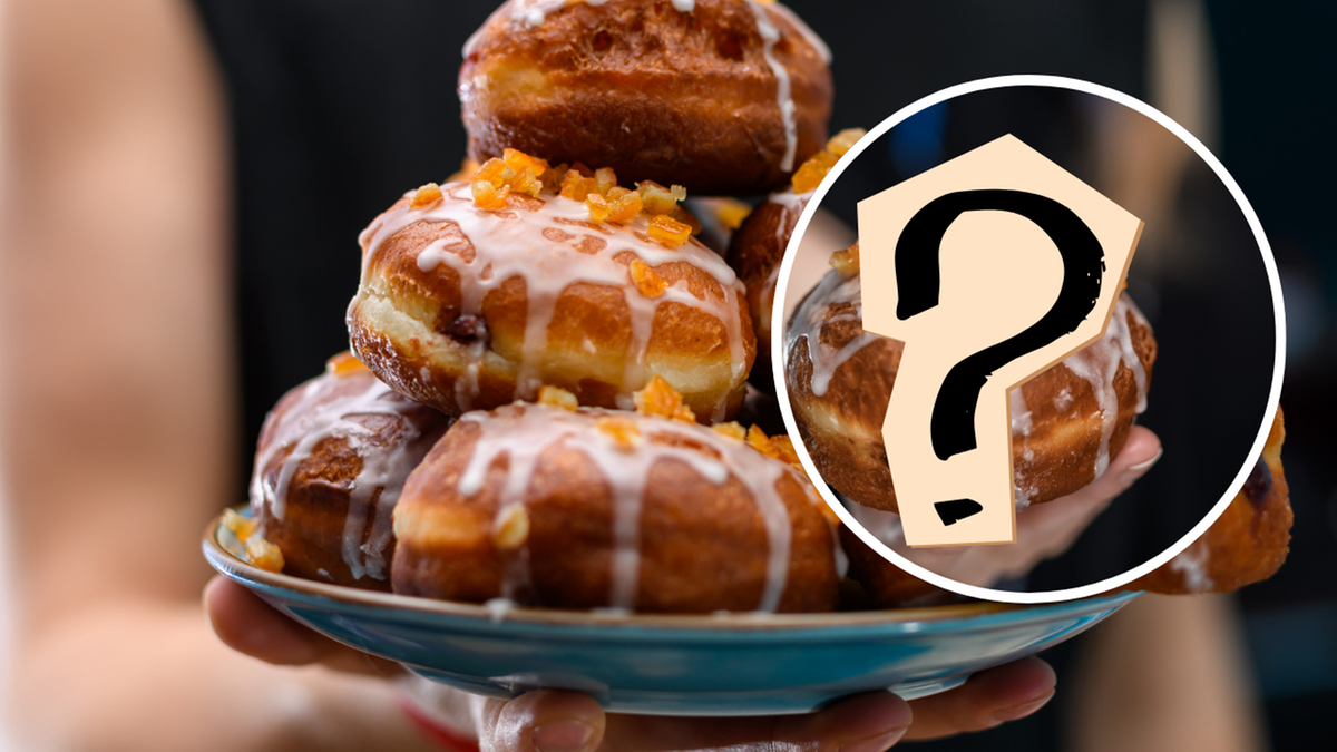 Stos pączk&oacute;w polanych lukrem i posypanych sk&oacute;rką pomarańczową.