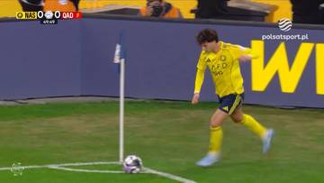 Piłkarz w ż&oacute;łtej koszulce wykonuje rzut rożny na boisku piłkarskim.