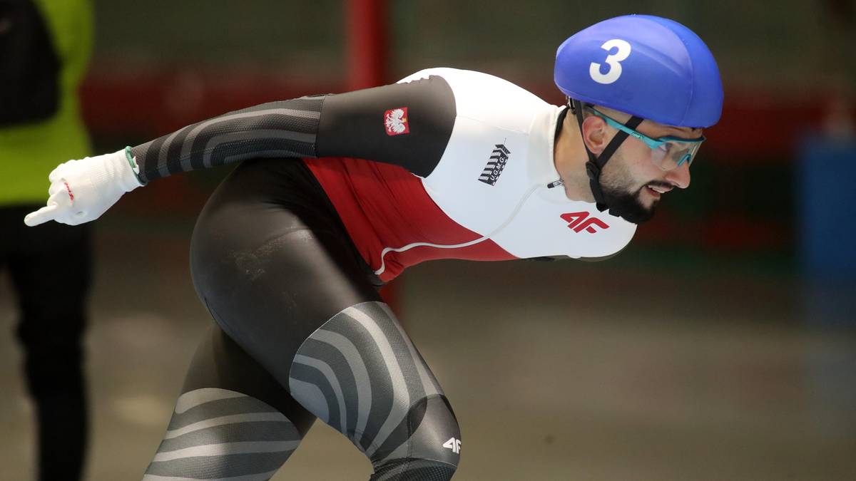 Zawodnik w kasku i stroju do łyżwiarstwa szybkiego w ruchu na torze.