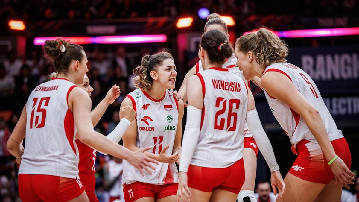 Pięć siatkarek w białych koszulkach z czerwonymi numerami i czerwonymi spodenkami świętuje na boisku.