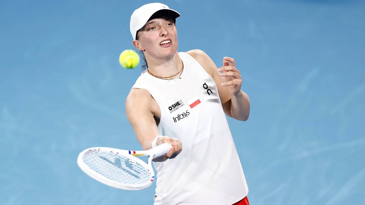 Iga Świątek podczas meczu tenisowego, uderzająca piłkę rakietą.