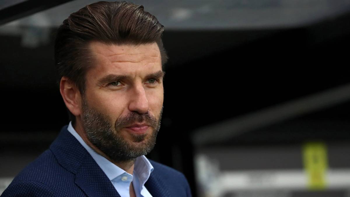 Portret mężczyzny, Jacka Magiery, nowego trenera Cracovii, w granatowym garniturze i jasnoniebieskiej koszuli.