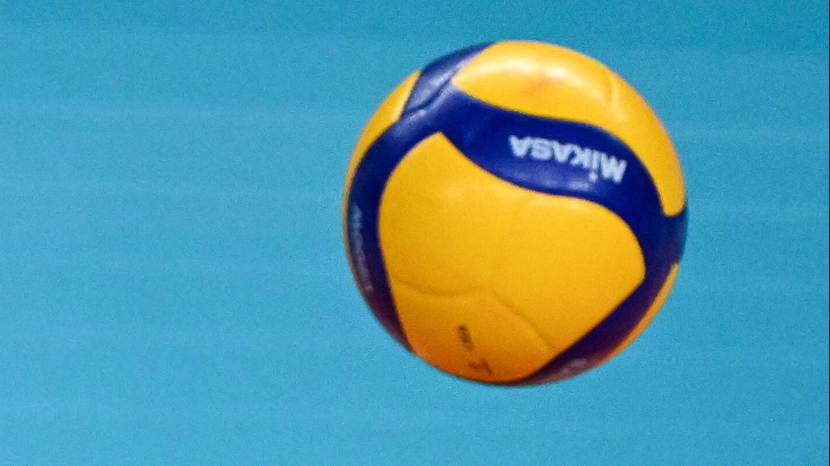 Piłka do siatk&oacute;wki Mikasa w ż&oacute;łto-niebieskich barwach na niebieskim tle.