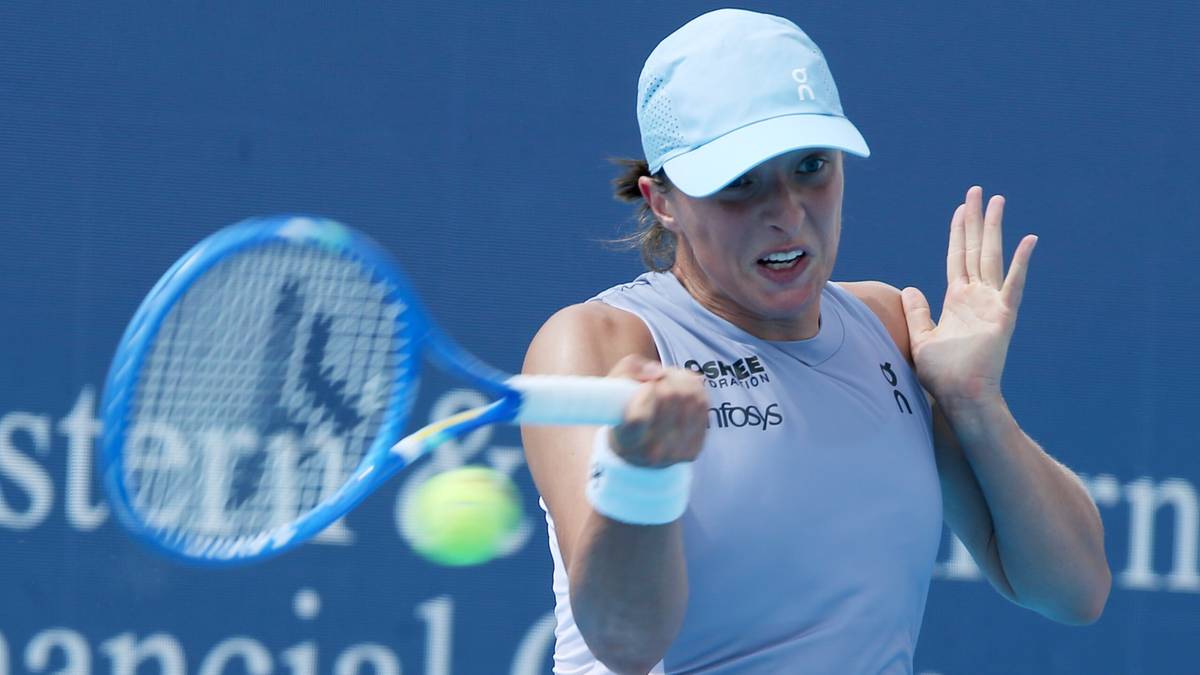 Iga Świątek uderza piłkę rakietą tenisową podczas meczu.