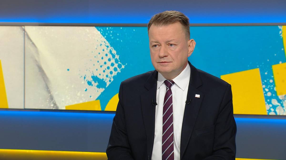 Mariusz Błaszczak w garniturze i krawacie siedzi w studiu telewizyjnym.