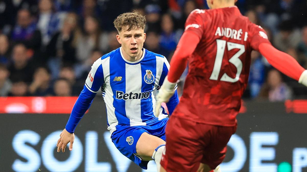 Piłkarz FC Porto w niebiesko-białym stroju walczy o piłkę z zawodnikiem w czerwonym stroju.