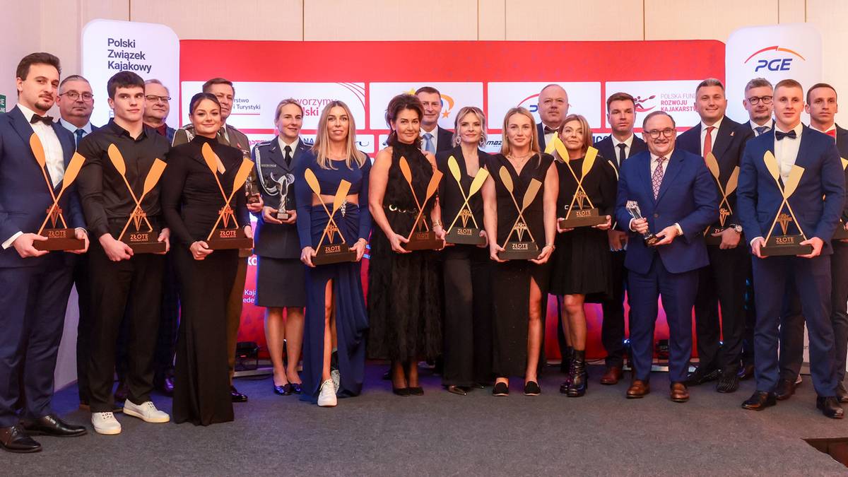 Grupa sportowc&oacute;w i działaczy w strojach galowych pozuje do zdjęcia, trzymając w rękach statuetki "Złote Wiosła".