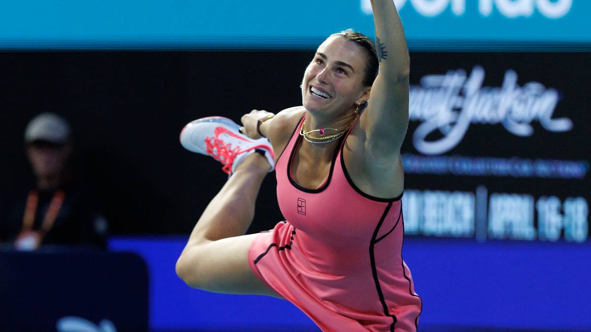 Tenisistka w r&oacute;żowym stroju wykonuje energiczne uderzenie podczas meczu tenisowego.