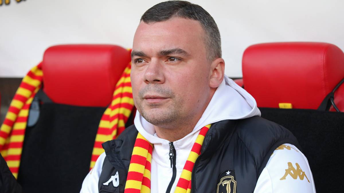 Portret Adriana Siemieńca, trenera piłkarskiego, w kurtce klubowej i szaliku.