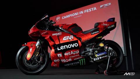 Czerwony motocykl wyścigowy Ducati MotoGP z widocznymi logotypami sponsor&oacute;w, stojący na podium z napisem "CAMPIONI IN FESTA".