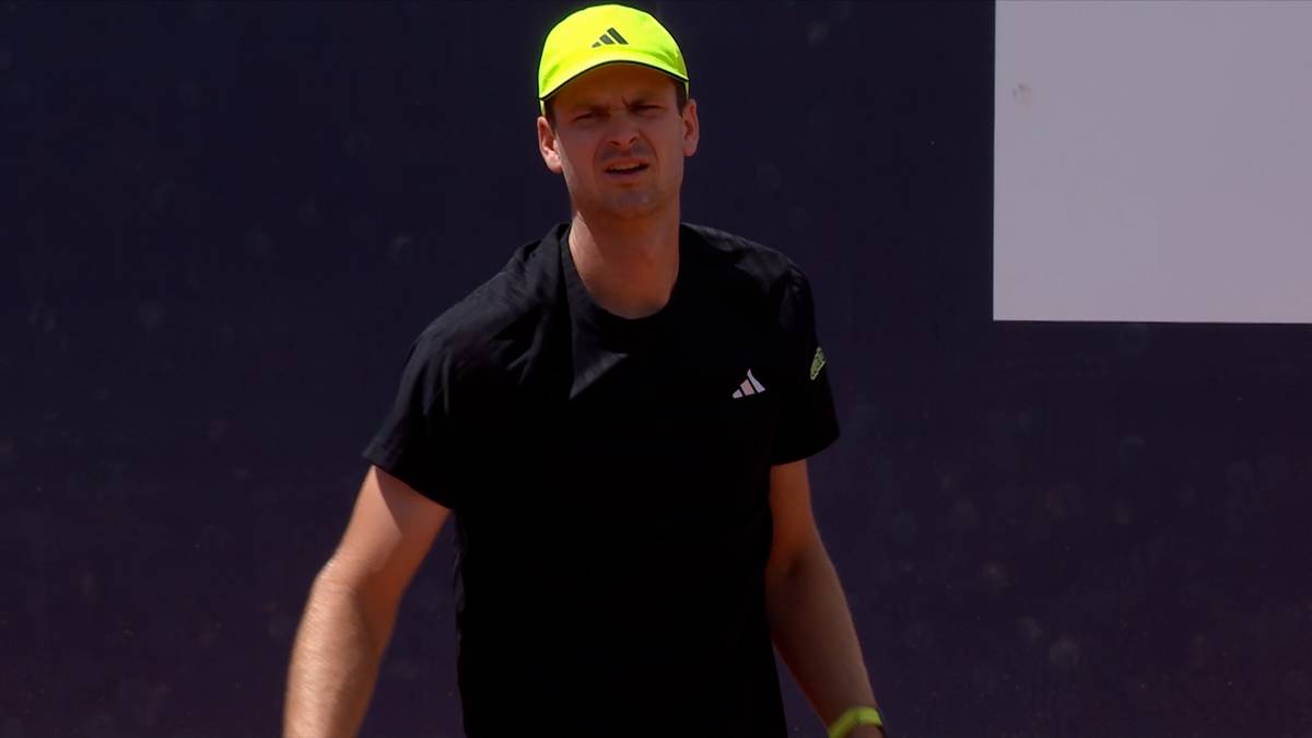 Hubert Hurkacz w żółtej czapce i czarnej koszulce na tle ciemnego tła.